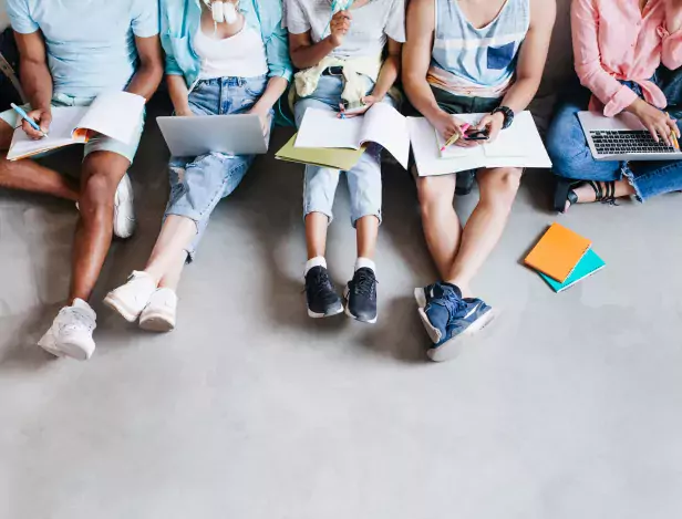 overhead-portrait-young-people-with-laptops-smartphones-sitting-together-floor-students-writing-lectures-holding-textbooks-their-knees